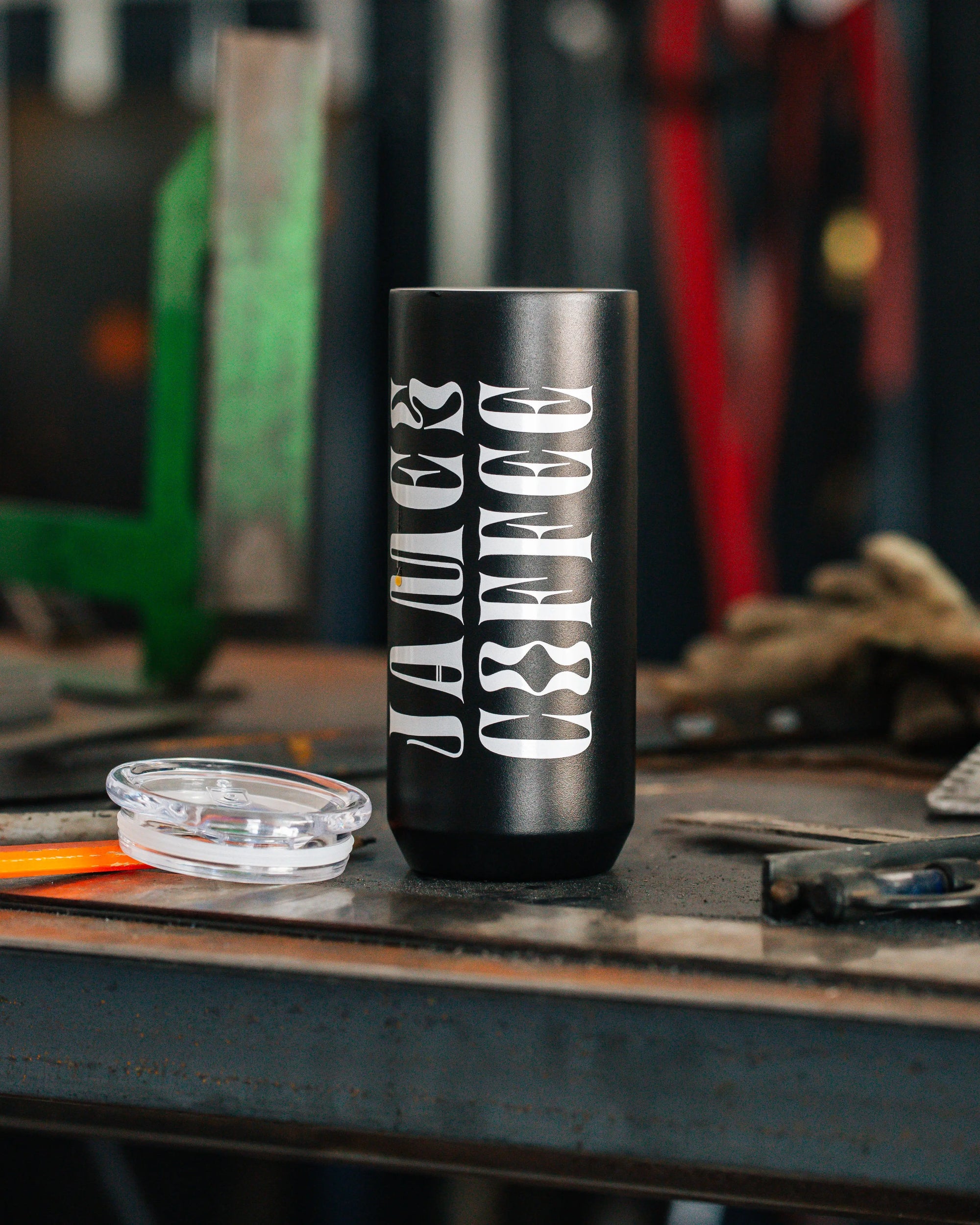 James Coffee Tumbler with Logo on it sitting on a work bench